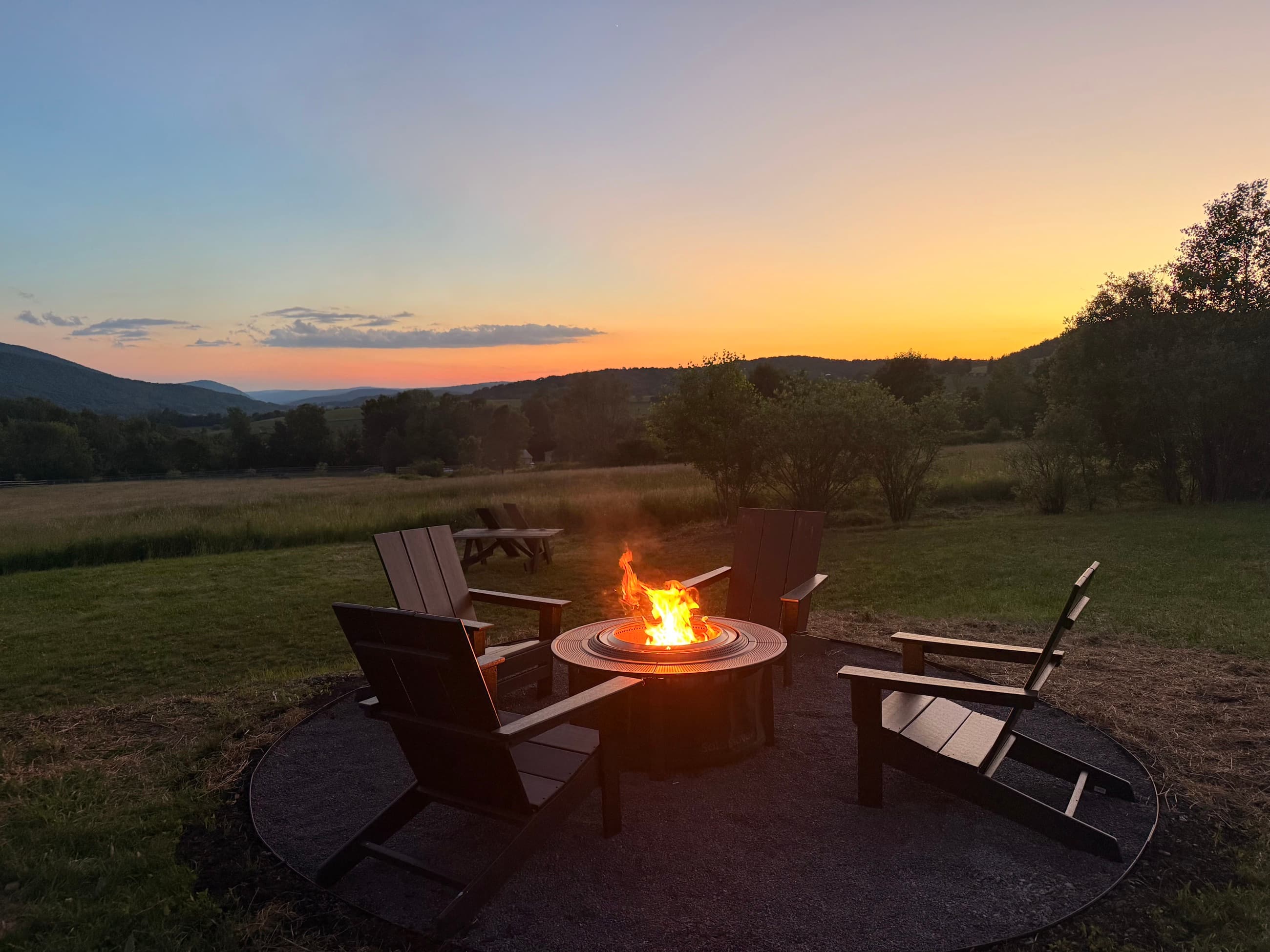 The firepit burning at dusk, the valley sinking into last light