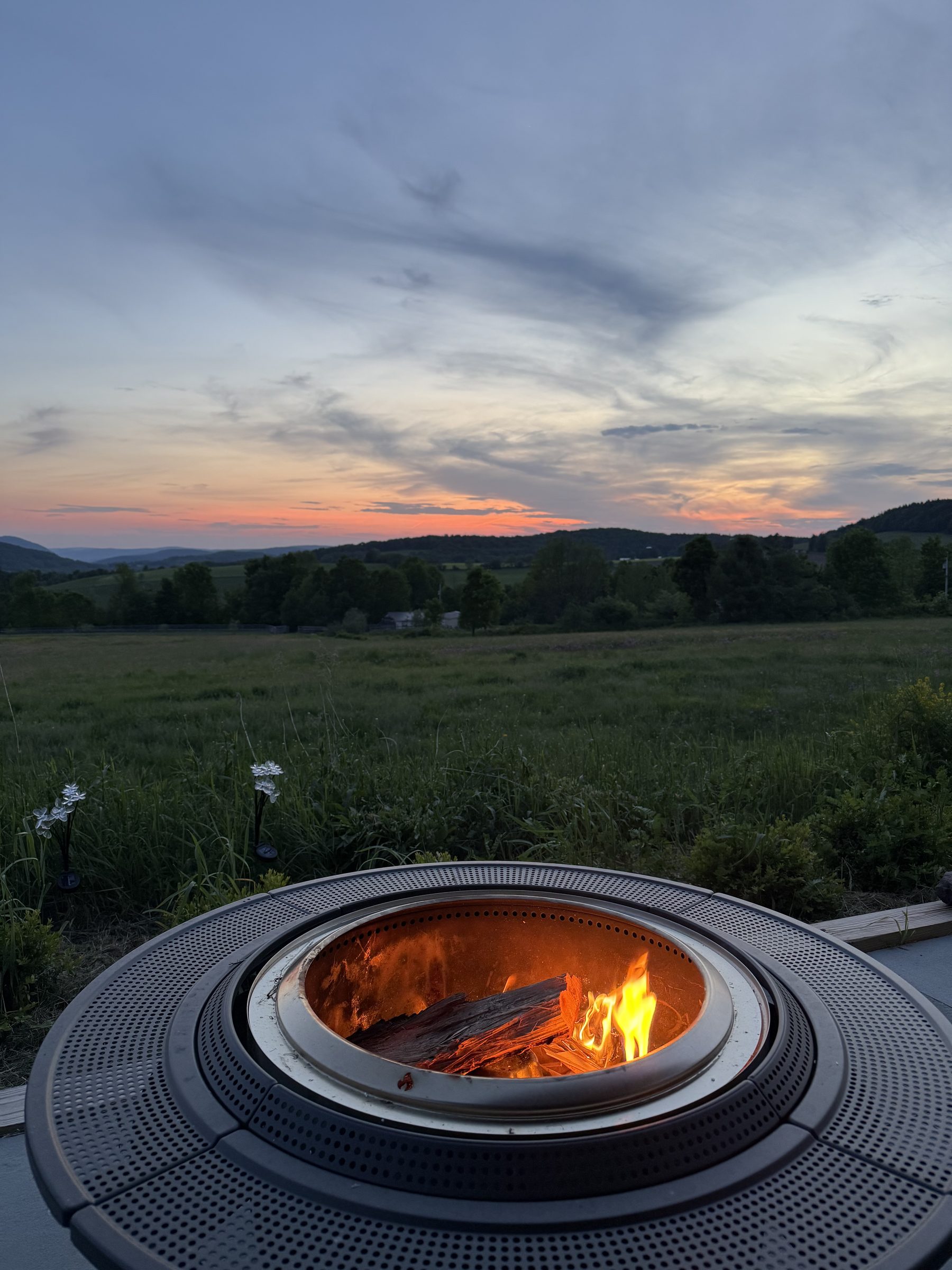 The firepit lit at dusk, sunset over the ridge